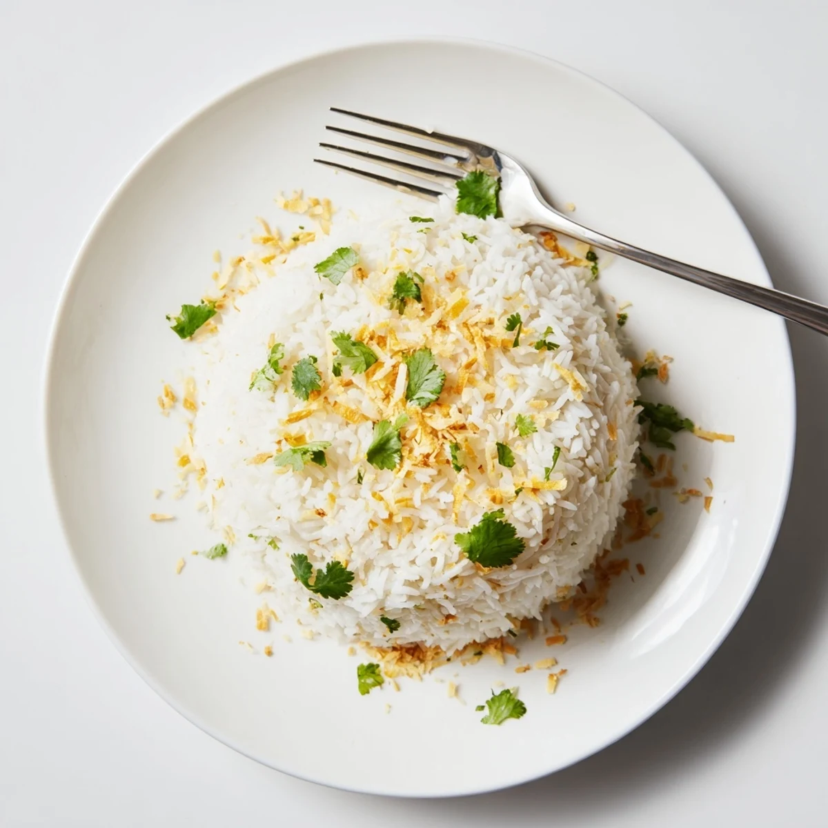 Steaming bowl of coconut rice garnished with toasted flakes and fresh cilantro