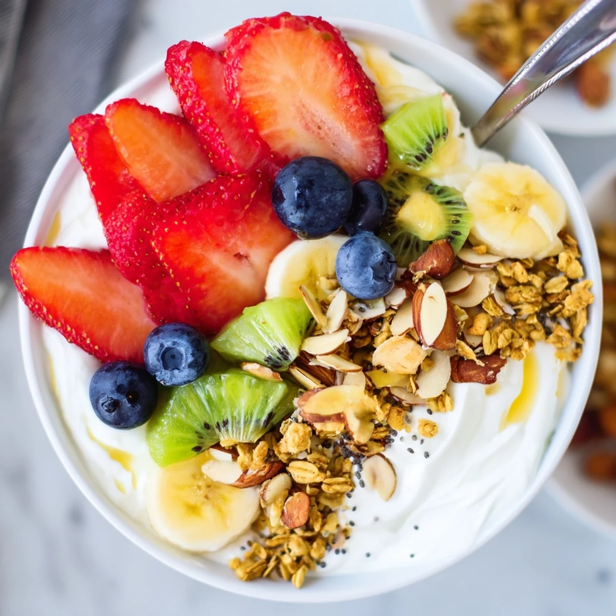 Vibrant yogurt fruit bowl served in a white dish with crunchy almond topping