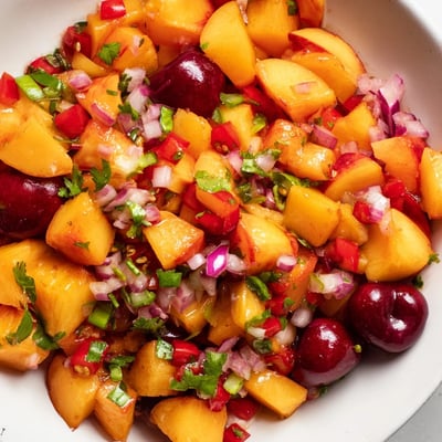 A close-up of Healthy Peach Cherry Salsa featuring sweet cherries, juicy peaches, red onion, and jalapeño, ready to serve with tortilla chips.