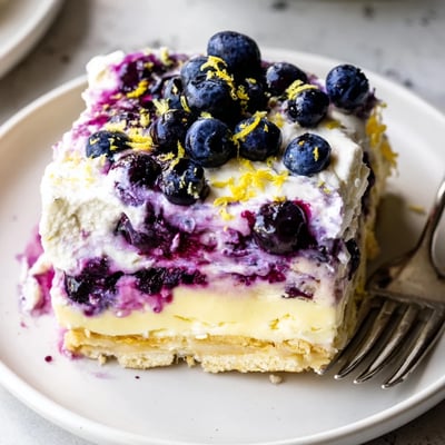 No-bake lemon blueberry lasagna in a glass dish topped with whipped cream and fresh berries