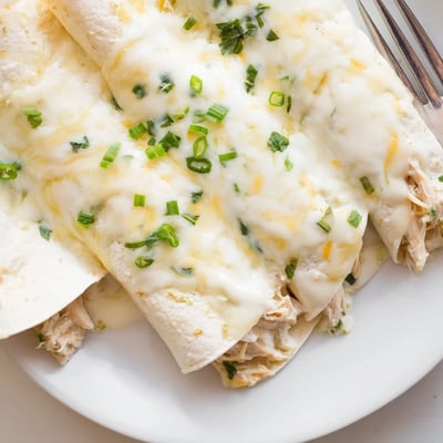 Sliced open Creamy White Chicken Enchiladas revealing velvety filling, warm tortillas.